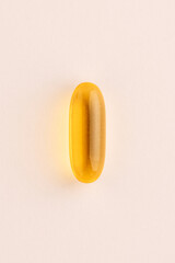 Centered yellow gel capsule macro on beige background modern minimal health nutrition concept. High quality photo