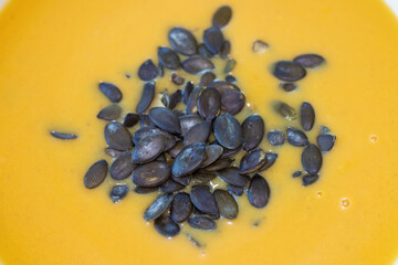 Pumpkin seeds floating on the surface of creamy pumpkin soup.