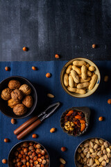 Bowls with nuts and blue table cloth on black chalkboard background. Flat lay. Top view.