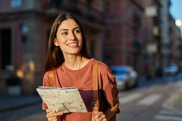 Portrait of a smiling young woman  looking at a map in the city, tourists visiting destination,...