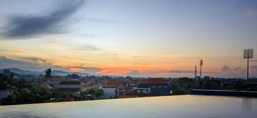 Obraz premium Beautiful sunset over a city with a pool in the middle