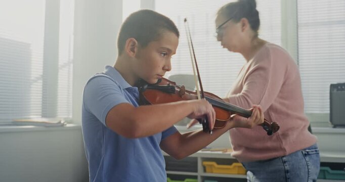 Primary School Boy Practicing Violin in Music Class, Dreaming to Become Musician. Teacher Guiding Artistic Child in Playing Musical Instrument. Musical Education, Violin Training Lesson, Rehearsal.
