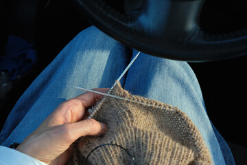 knitting sweater in brown color, while sitting in a car