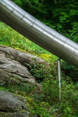 Metal tube slide descending over rocks and greenery.