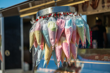 Colorful cotton candy bags hanging at outdoor market.