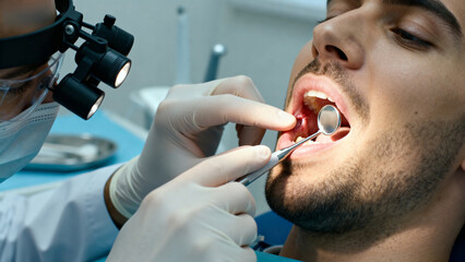 Dentist examining a patient's teeth using dental tools in a clinical setting