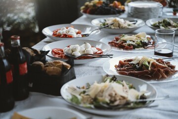 An inviting spread of Italian dishes featuring fresh mozzarella, sliced tomatoes, and prosciutto. The table is set for a delicious feast with carbonated beverages on the side