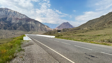 Wide mountain highway under blue sky leading toward peaks