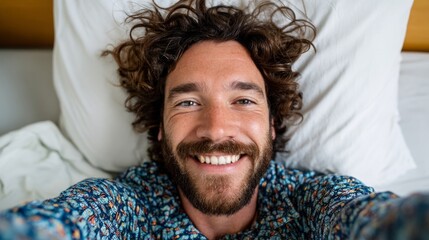 Man smiling in bed, taking selfie.