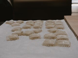 Close up overhead shot of hands carefully forming fresh uncooked Italian tortelli pasta on a clean white surface