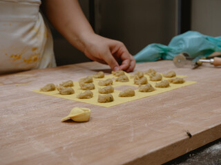 Artisan Chef Carefully Crafts Delicious Italian Tortelli Pasta Dough Squares on Wooden Surface in Professional Kitchen