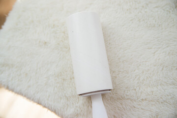 A woman's hand cleans the white soft surface of the furniture with a sticky roller. Cleaning of upholstered furniture from dust, wool and hair.
