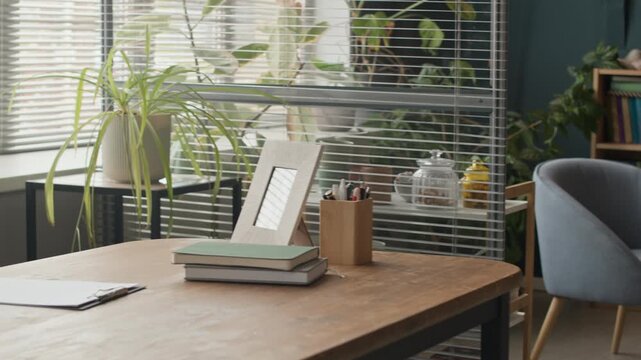 No people pan shot of modern therapy office interior with comfortable armchairs around small coffee table providing relaxed setting for individual sessions and work desk by window behind partition