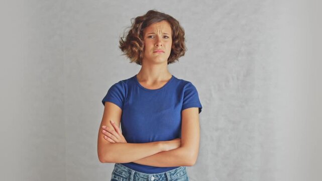 Doubtful young girl raising eyebrow with crossed arms showing skepticism and critical assessment. Ideal for doubt and critical assessment content