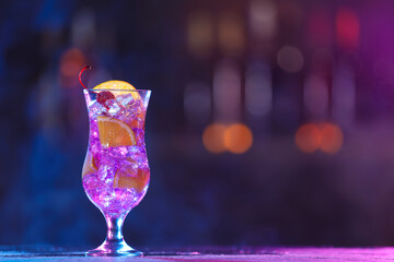 Glass of alcoholic cocktail on table against blurred background with smoke, space for text