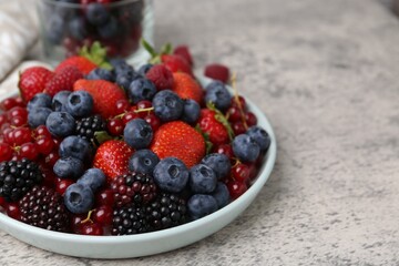 Different ripe berries on light grey textured table, closeup. Space for text