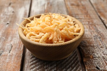 Dried squid shavings in bowl on color wooden table, closeup
