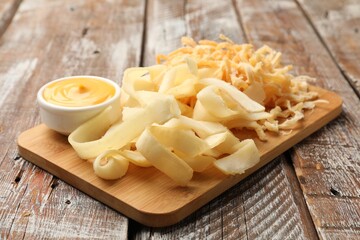 Dried shredded squid, shavings and sauce on color wooden table, closeup