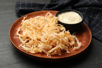 Tasty dried squid shavings and sauce on black table, closeup