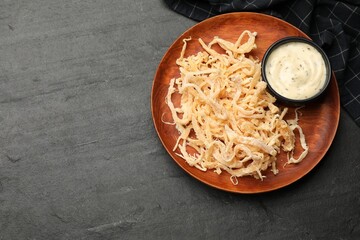 Tasty dried squid shavings and sauce on black table, top view. Space for text