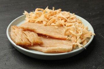 Tasty dried squid on black table, closeup