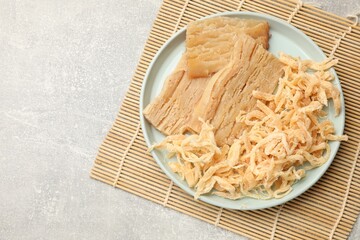 Different tasty dried squid on grey table, top view. Space for text