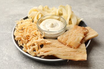 Tasty dried squid and sauce on grey table, closeup