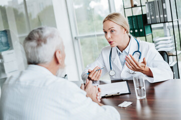 Fototapeta premium Professional physician consulting an elderly patient during a medical appointment in a modern clinic office