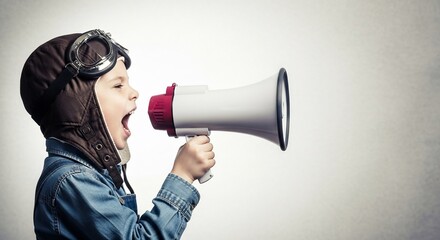Young boy in a pilot hat making his voice heard with a megaphone