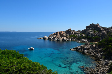 Rocky coastline of Capo Testa in Sardinia, with turquoise waters, granite cliffs, green vegetation and cloudless sunny sky