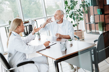 Obraz premium Senior Patient Discussing Health Concerns with a Female Doctor in a Bright Medical Office Setting