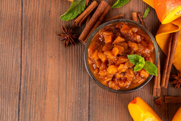 Homemade sweet autumn Pumpkin Chutney, with brown sugar, cinnamon, on white wooden background with ingredients for cooking - pumpkin squash, spices, honey