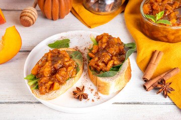 Tasty autumn toast sandwiches with spicy pumpkin chutney and spinach, healthy snack idea for fall brunch