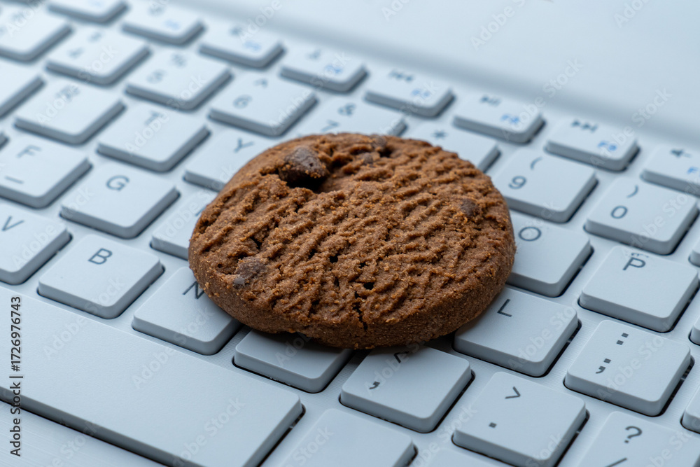 Wall mural close-up of a cookie on a computer keyboard. internet cookies, technology, and online privacy concep