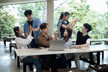 Joyful diversity of college students cheering and congratulating each other, showing unity and accomplishment in a group assignment session