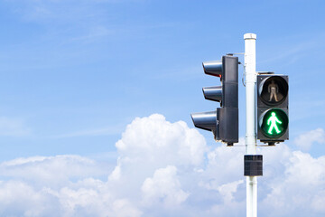 Traffic lights with green or red light lit hanging on steel pole with blue sky cloud white is background. Safety with people to traffic. Sign or symbol pedestrians not allowed crossing road. 