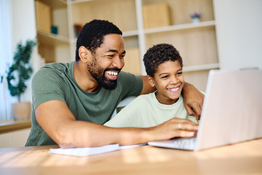 Father and son doing homework with laptop at home. Father and teenage son using laptop. Boy and dad sitting at home working with notebook