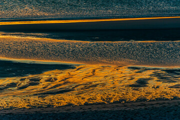 Abendsonne spiegelt sich bei Ebbe im Wattenmeer vor der Nordseeinsel Sylt