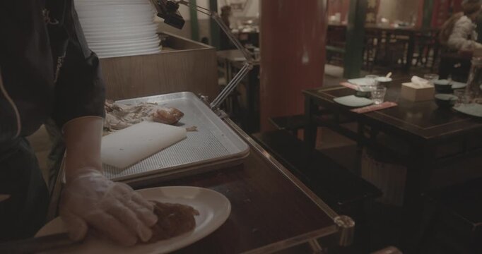 chef skillfully Peking duck slices succulent meat for an eager crowd, showcasing expertise.