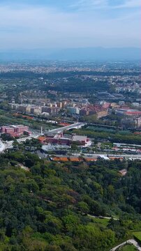 Stunning 4K aerial vertical video footage of Rome's skyline from Janiculum Hill. Drone captures lush green parks, Tiber River, historic buildings, distant mountains in vibrant urban panorama.