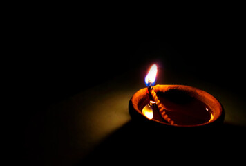 Single Clay Oil Lamp Glowing in Darkness