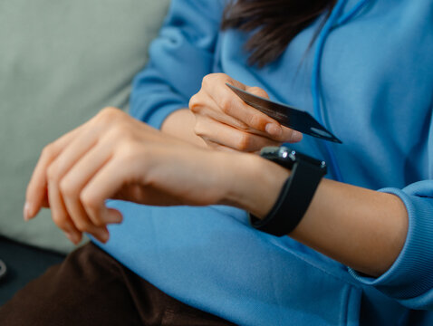 Close-Up of Asian Female Hands Using Smartwatch and Credit Card for Digital Payment, Cashless Transaction Concept. Asian Female Holding Credit Card and Tapping Smartwatch Making Online payment. - Powered by Adobe