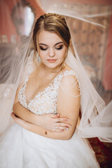 Fototapeta premium Bride in lace wedding dress with veil smiles. Her joyful expression radiates happiness and love on her wedding day.