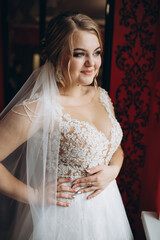Naklejka premium Bride in lace wedding dress with veil smiles. Her joyful expression radiates happiness and love on her wedding day.