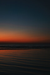 Fototapeta premium Tranquil seascape at sunset with vivid orange and blue gradient sky reflecting on calm ocean waves