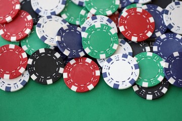 Casino gaming background with stacks of betting chips of different colors on green gaming mat