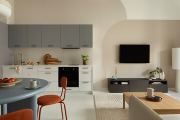 Modern kitchen and living area with TV, grey cabinets, wooden coffee table and neutral palette.