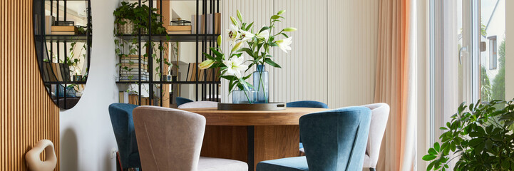 Stylish composition of elegant dining room interior design with velvet armchairs, design rouded wooden table and beautiful personal accessories. Glamour interior design inspiration. Template.