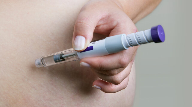 Weight loss and diabetes treatment. Person using Mounjaro insulin injector pen or GLP-1 injection for shot in abdomen. Obesity therapy, hormonal medication, semaglutide injection, modern healthcare