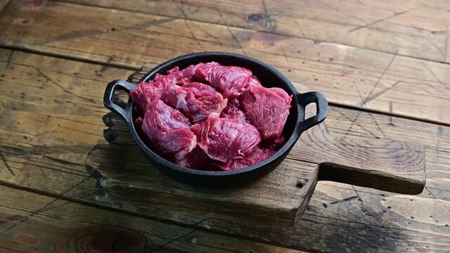 Cooking beef chunks in a skillet on a wooden countertop for a homemade meal